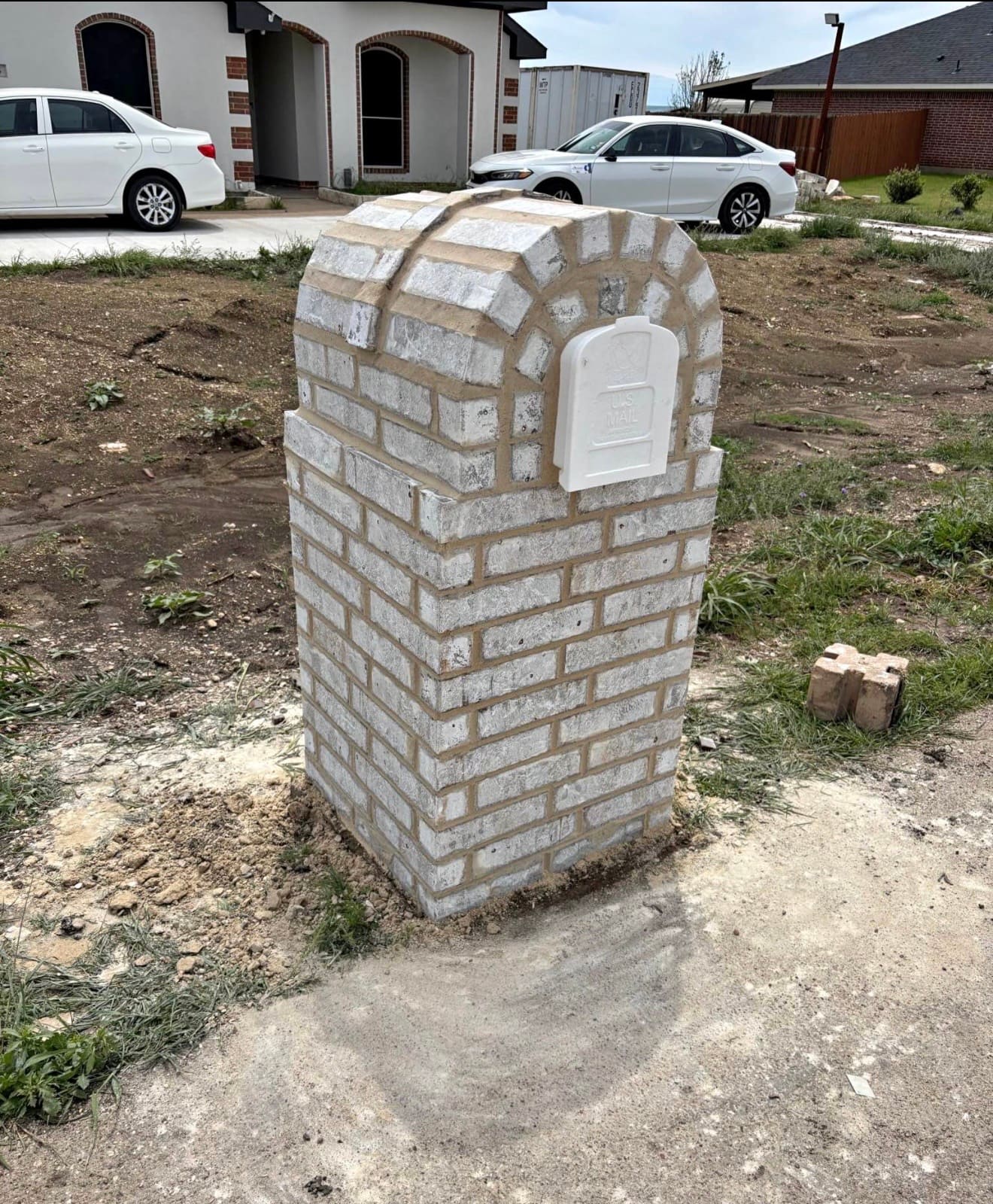 Limewashed brick mailbox column with an arched recessed panel