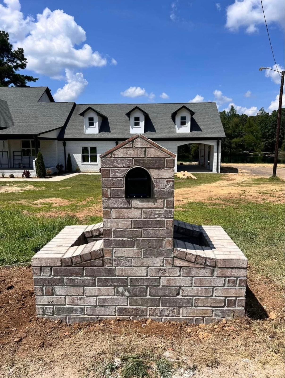 Brick mailbox column with an arched niche on a raised brick planter base