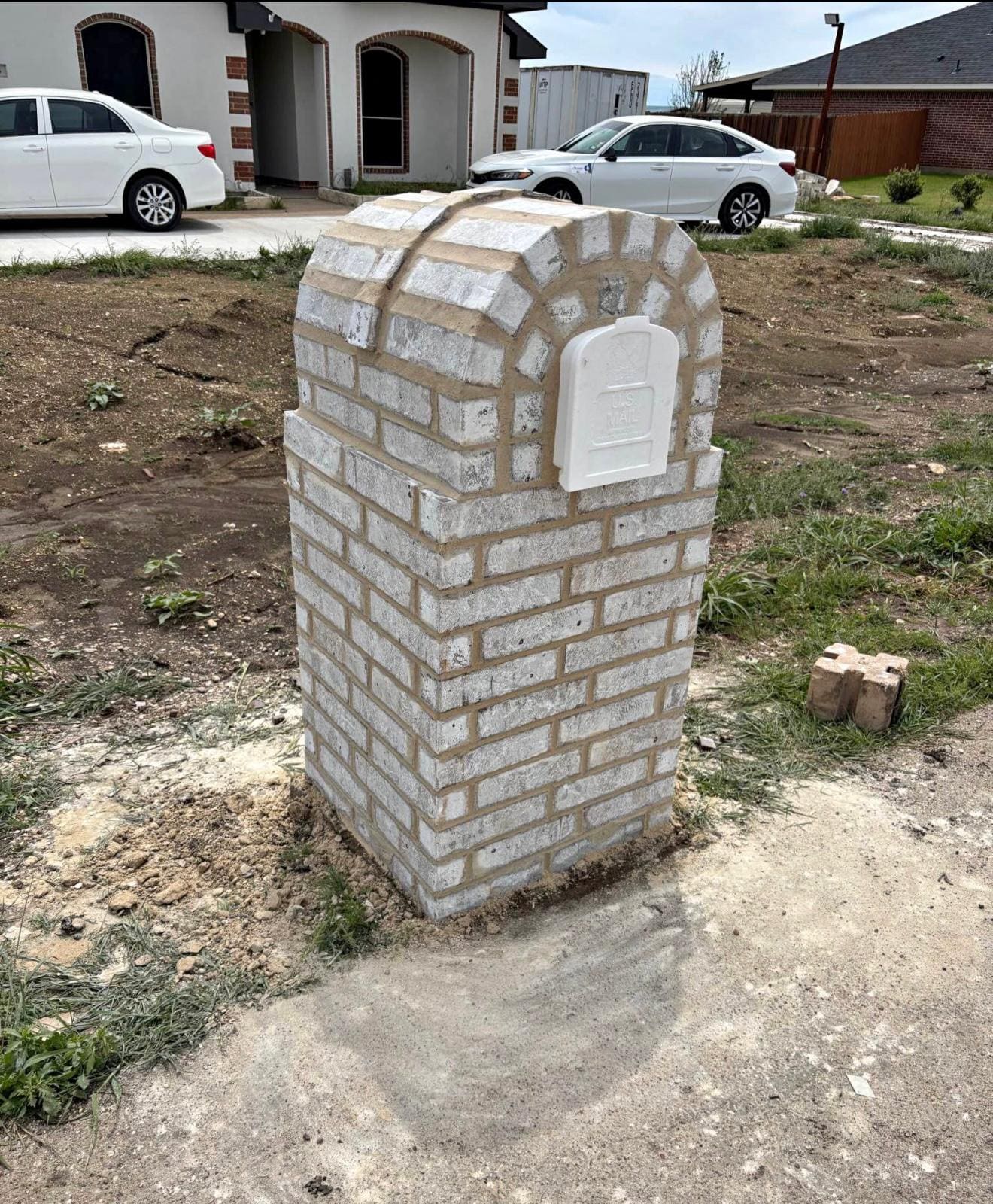 Limewashed brick mailbox column with an arched recessed panel